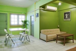 a living room with green walls and a couch and a table at GO INN The Grand Palace - Mrt Samyot Station in Bangkok