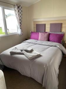 1 dormitorio con 1 cama grande con almohadas moradas en Emma's Oasis 4-bedroom caravan at Durdle Door, en West Lulworth