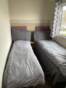 1 dormitorio con 2 camas y ventana en Emma's Oasis 4-bedroom caravan at Durdle Door, en West Lulworth
