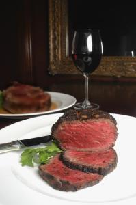 a piece of steak on a plate with a glass of wine at Market Pavilion Hotel in Charleston