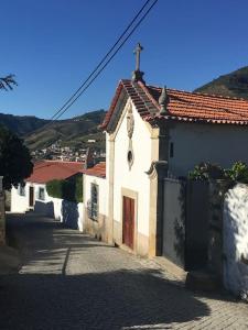 a small white building with a door on a street at casa das ameias in Folgosa