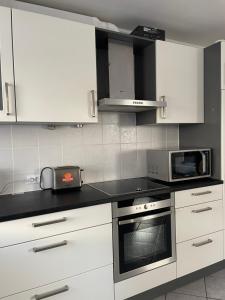 a kitchen with white cabinets and a microwave at Large Room Free Parking 10mins to Luxembourg Airport Excellent Customer Service in Luxembourg