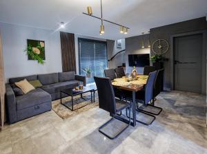 a living room with a couch and a table and chairs at TRZY SOSNY LOFT APARTMENTS in Ściegny