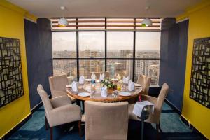 a dining room with a table and chairs and a large window at Golden Tulip Dar Es Salaam City Center Hotel in Dar es Salaam