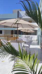 a patio with tables and umbrellas on a building at HOTEL KICHARME PONTAL in Fortim