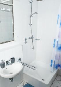a white bathroom with a shower and a sink at Hotel Granitz in Binz