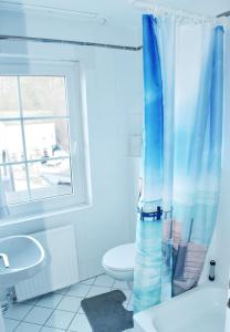 a bathroom with a blue shower curtain and a toilet at Hotel Granitz in Binz