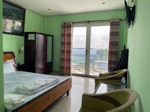 sypialnia z łóżkiem, 2 krzesłami i oknem w obiekcie Bảo Bảo Hotel w mieście Châu Đốc
