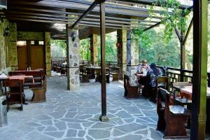 a restaurant with wooden tables and people sitting at tables at Семеен Хотел Ажур in Kotel