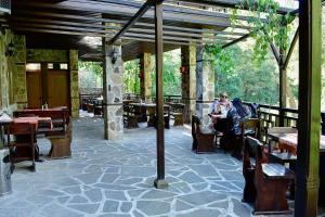 un restaurant avec des tables en bois et des personnes assises à table dans l'établissement Хотел Ажур, à Kotel