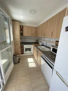 a kitchen with wooden cabinets and a sink and a refrigerator at Casa cactus Piles Playa in Piles