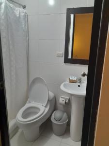 a white bathroom with a toilet and a sink at Margarita's House Machupicchu in Machu Picchu