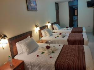 マチュピチュにあるMargarita's House Machupicchuのホテルルーム 花の飾られたベッド2台付