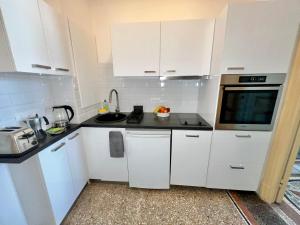 a small kitchen with white cabinets and a microwave at Résidence La Villa Léonie in Nice