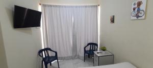 1 dormitorio con 2 sillas, 1 cama y TV en Alojamiento Acogedor en San Felipe de Puerto Plata