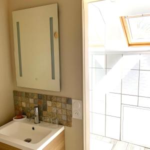 La salle de bains est pourvue d'un lavabo, d'un miroir et d'une fenêtre. dans l'établissement La Bigourdane, à Gerde