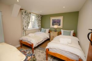 2 camas en una habitación con paredes verdes en Carters Cottage - Rudge Farm Cottages, en Bridport