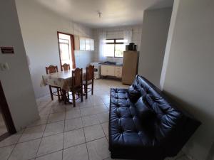 een woonkamer met een zwarte leren bank en een tafel bij Residencial Medeiros in Guarda do Embaú