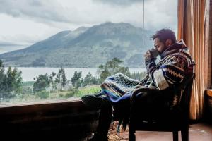 un hombre sentado en una silla hablando por celular en Cabañas y Glampings Balcon del lago, en Otavalo