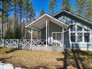 a gray house with a large porch in the woods at Golfhelmi in Savonlinna