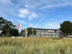 ein großes Gebäude auf einem Feld mit einem hohen Gras in der Unterkunft Bellevue Nr. 15 in Scharbeutz