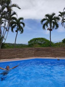 een man zwemmend in een zwembad met palmbomen bij Finca Colibri écolodges en nature Costa Rica in Cabo Blanco