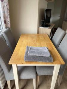 a wooden table with chairs and a towel on it at Emma's Oasis 4-bedroom caravan at Durdle Door in West Lulworth