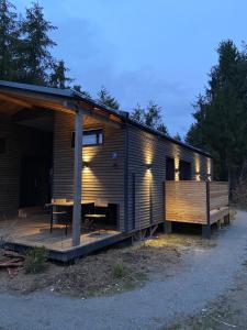 Cette petite cabine dispose d'une terrasse en bois avec une table. dans l'établissement Modernes Tinyhouse Trailer Cabins am Waldrand - mit Seezugang, à Eging am See