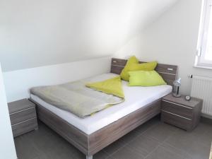 una cama con almohadas amarillas en una habitación en Fewo Steinhohle, DG 45qm, 1 Schlafzimmer & 1 Wohn-Esszimmer mit Bett, en Sulzbach am Main