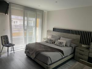 um quarto com uma cama, uma cadeira e uma janela em Apartamento Maitika em Santander