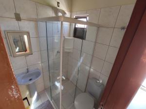a bathroom with a shower and a toilet and a sink at Residencial Medeiros in Guarda do Embaú