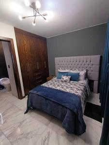 1 dormitorio con 1 cama grande con almohadas azules en moderno apartamento en el centro de la ciudad en Chihuahua