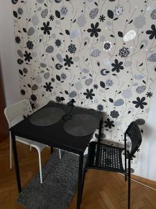 einen schwarzen Tisch und zwei Stühle vor einer Wand in der Unterkunft Mala Bella in Zemun