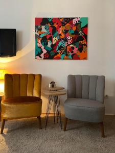 2 Stühle und ein Tisch in einem Zimmer mit einem Gemälde in der Unterkunft Mala Bella in Zemun