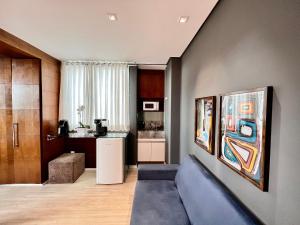 a living room with a couch and a kitchen at Flat em região nobre in Belo Horizonte