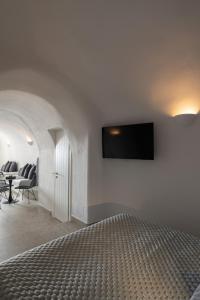 a bedroom with a flat screen tv on a wall at Nisó Cave Suites in Megalokhori