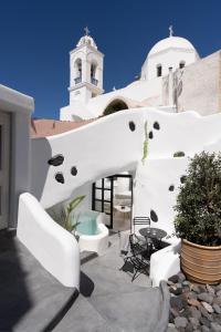 uma casa branca com uma escada e uma torre em Nisó Cave Suites em Megalochori