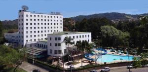 a large white building with a pool in front of it at Hotel Brasil in São Lourenço