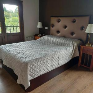 a bedroom with a bed with a white comforter and a window at La Quintana de Mary in Aramil de Arriba