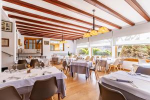 a restaurant with white tables and chairs and large windows at Hotel del Prado in Puigcerdà