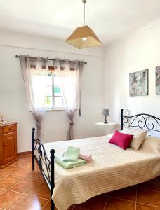 Schlafzimmer mit einem Bett mit rosa und grünen Kissen in der Unterkunft Sweet Home of Cabanas in Conceição