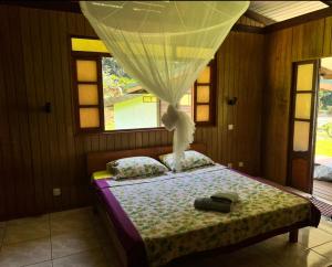 a bedroom with a bed with a curtain above it at Te Fare Manulani in Uturoa