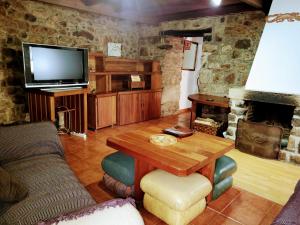 ein Wohnzimmer mit einem Holztisch und einem TV in der Unterkunft Casa Ferreira, Senda del Oso in Oviedo