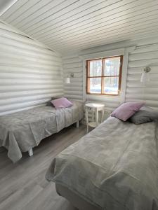 a bedroom with two beds and a table and a window at Bastöstugby stuga 17 in Pålsböle