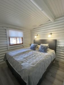 a bedroom with a large bed with blue pillows at Bastöstugby stuga 17 in Pålsböle
