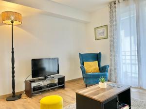 uma sala de estar com uma televisão e uma cadeira azul em LA LOUSIANE - Confort - Wifi - Parking privé - Terrasse - Centre Ville em Quimper