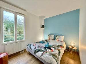 um quarto com uma cama com uma parede azul em LA LOUSIANE - Confort - Wifi - Parking privé - Terrasse - Centre Ville em Quimper