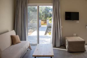 een woonkamer met een bank en een glazen schuifdeur bij Casa De Rosa Apartments & Studios in Svoronata