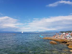 a group of people sitting on a beach in the water at ReginaMare Santa in Piran