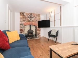 ein Wohnzimmer mit einer blauen Couch und einem Kamin in der Unterkunft Grants Cottage in Dartmouth
